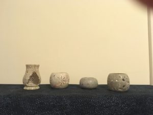 Photograph of four stone candle holders of different shapes but the same pale gray stone.