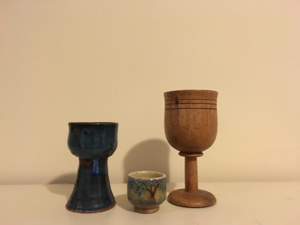 Photograph of three chalices: one smaller blue pottery, one very small offering cup with a tree in glazes, and one carved from wood.