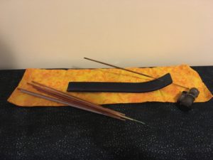 Photograph of incense stick holder, loose sticks, and lighter.