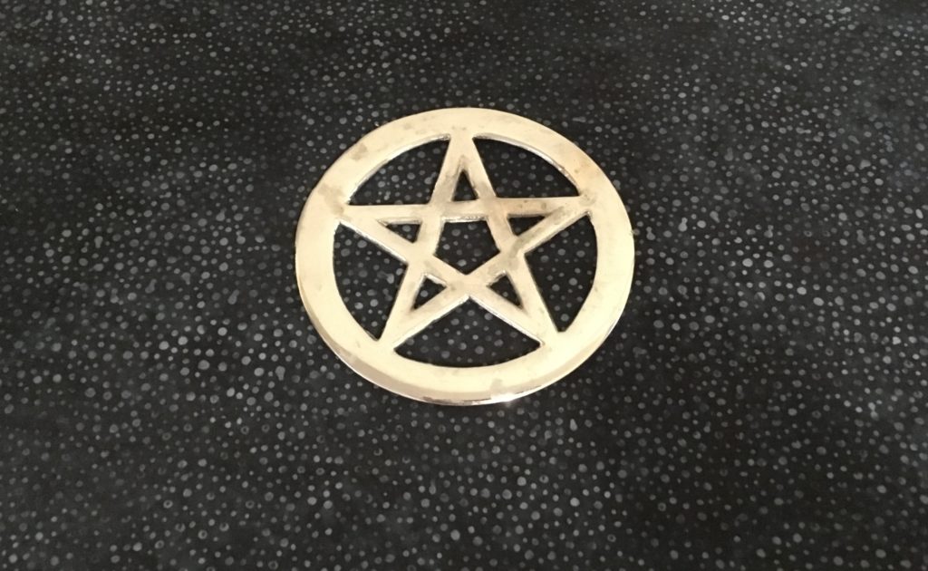 Photograph of silver metal pentacle on blue and gray altar cloth